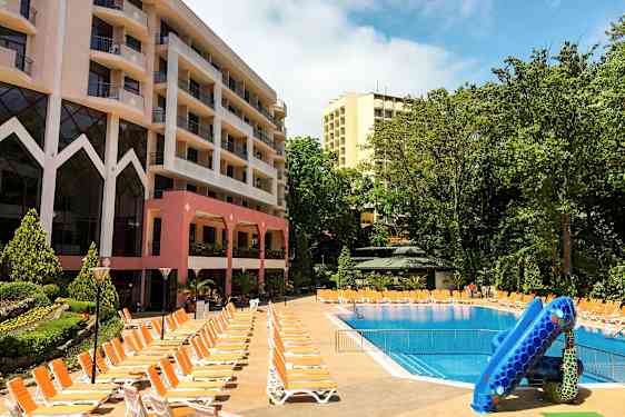 Hotellbyggnader vid en utomhuspool med solstolar och vattenrutschbana. (AI-genererad text)