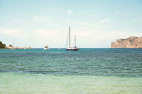 En klarblå himmel ovanför en havsvy med segelbåtar på vattnet och en klippig kust i bakgrunden. (AI-genererad text)