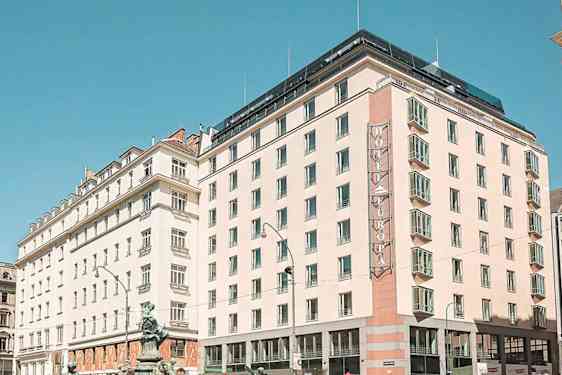 En stadsscen med flera byggnader, inklusive ett hotell med skylten "Hotel Europa", under en klar blå himmel. (AI-genererad text)