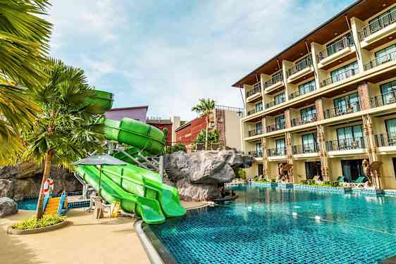 Hotellpool med gröna rutschkanor och en byggnad i bakgrunden. (AI-genererad text)