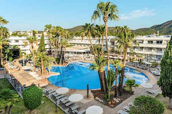 En hotellpool omgivet av solsängar och parasoller, med palmer och byggnader i bakgrunden. (AI-genererad text)