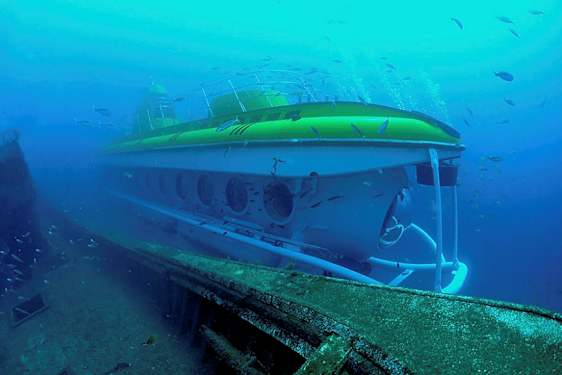 En undervattensbild av en ubåt nära ett skeppsvrak, omgiven av fiskar. (AI-genererad text)