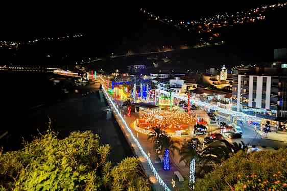 Stad vid havet nattetid med belysning och dekorationer. (AI-genererad text)