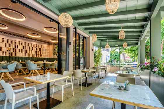Modern restaurang med utomhus- och inomhus sittplatser. (AI-genererad text)