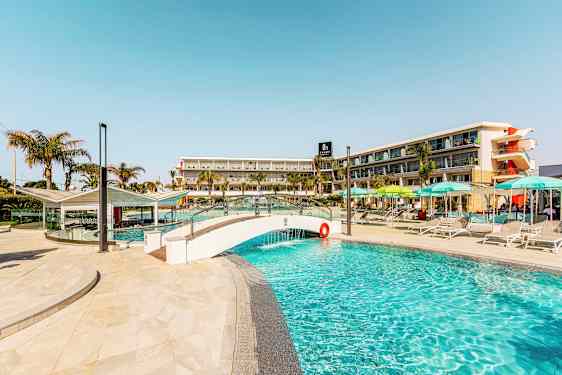 Bild av en pool, med en liten bro och hotellbyggnad i bakgrunden. (AI-genererad text)