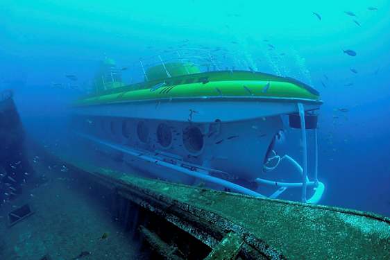 Undervattensutsikt av en ubåt bredvid ett gammalt skeppsvrak omgivet av fiskar. (AI-genererad text)