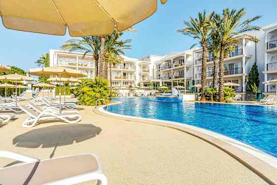 En utomhuspool omgiven av solstolar och parasoller med hotellbyggnader i bakgrunden. (AI-genererad text)