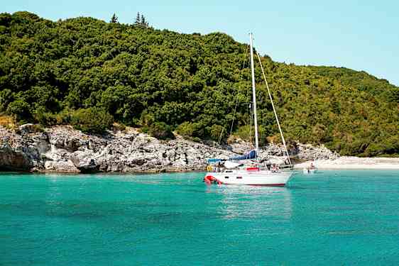 Segelbåt på turkost vatten nära en grönskande strand. (AI-genererad text)