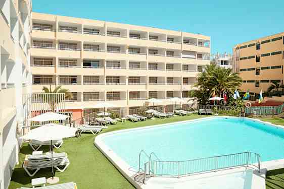 Hotellbyggnad med pool och solstolar utomhus. (AI-genererad text)