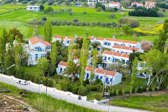 Flygbild av vita byggnader med röda tak omgivna av grönska och ett landskap. (AI-genererad text)