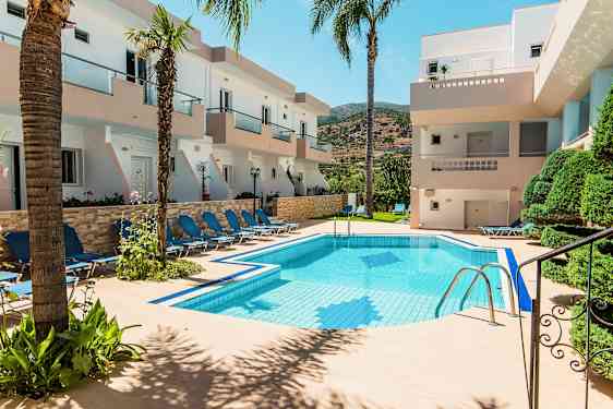 Bild av en pool omgiven av solstolar och byggnader med balkonger. (AI-genererad text)