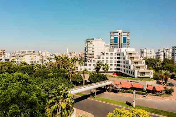 En modern byggnad omgiven av grönskande träd och stadsmiljö. (AI-genererad text)