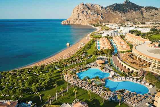 Flygvy över ett hotellområde med pooler, grönområden och en närligande strand vid havet. (AI-genererad text)