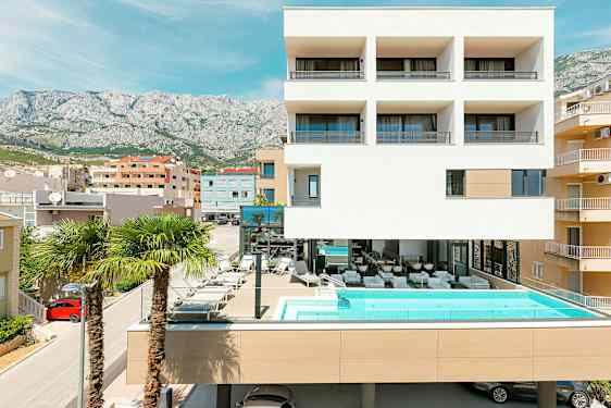 Modern byggnad med pool och palmer framför. (AI-genererad text)