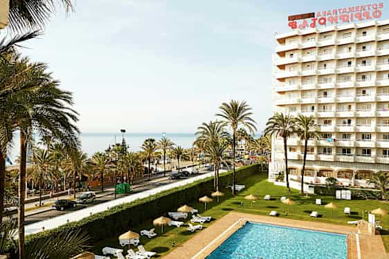 Bild av ett hotell med pool, palmer och utsikt över havet. (AI-genererad text)