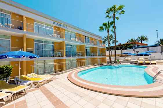 En utomhuspool med solstolar nära en lägenhetsbyggnad och palmer. (AI-genererad text)