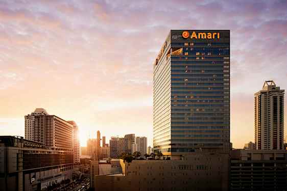 En stadsvy vid solnedgången med höghus och byggnader dominerar landskapet. (AI-genererad text)