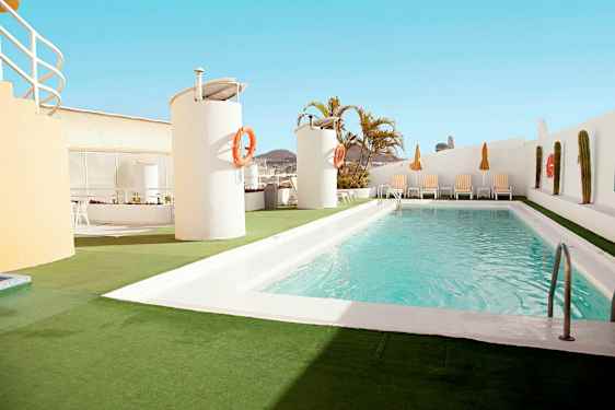 En utomhuspool ligger på en takterrass med solstolar och parasoller runt omkring. (AI-genererad text)