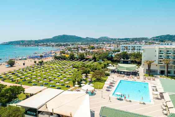 Vykort med en utsikt över en strand, hotellets poolområde och grönområden med parasoller. (AI-genererad text)