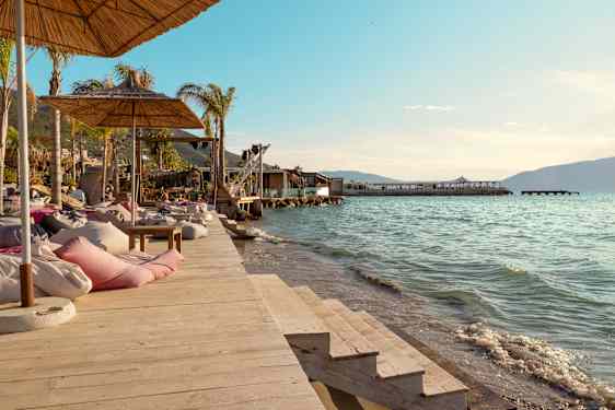 Solstolar och parasoll på en träbrygga vid vattnet. (AI-genererad text)