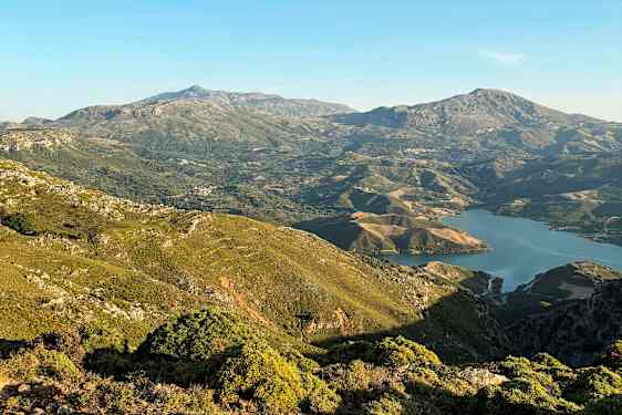 Vy över grönskande berg och en sjö i dalgången under en klar himmel. (AI-genererad text)