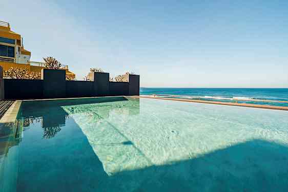 En infinitypool med utsikt över havet under en klar himmel. (AI-genererad text)
