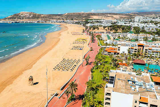 Strand med rad av parasoller och havet i bakgrunden. (AI-genererad text)