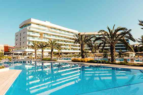 Hotell med pool och palmer i ett soligt område. (AI-genererad text)