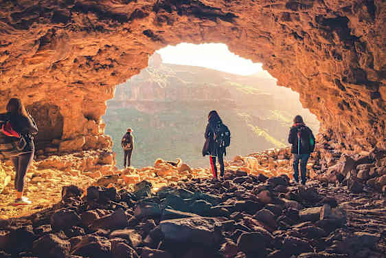 En grupp människor utforskar en grotta med utsikt över ett bergigt landskap. (AI-genererad text)