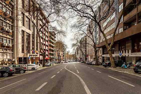 En bild av en tom stadsgata kantad av byggnader och träd. (AI-genererad text)