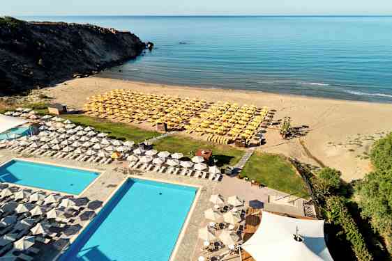 Hotellpool och solstolar nära sandstrand med havsutsikt. (AI-genererad text)