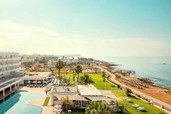 Bild som visar ett hotellområde med pool och grönområden i närheten av havet. (AI-genererad text)