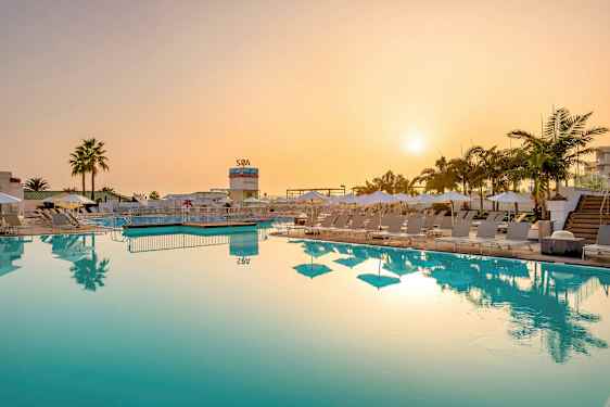 Poolområde med solstolar och parasoller vid solnedgången. (AI-genererad text)