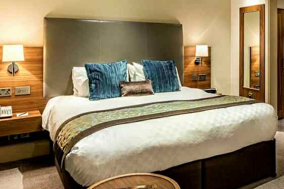 Bild av ett hotellrum med en dubbelsäng, sängbord och garderob i trä. (AI-genererad text)