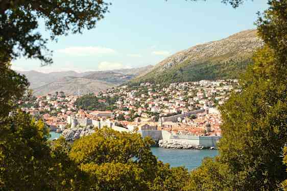 En vy över Dubrovnik med sin historiska stadsmur, omgiven av grönska. (AI-genererad text)
