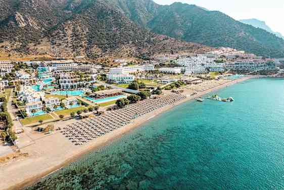 Flygfoto av en kustlinje med hotellkomplex vid stranden, pooler och solstolar. (AI-genererad text)