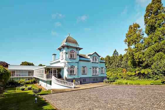 En ljusblå byggnad med stora fönster och gröna omgivningar. (AI-genererad text)