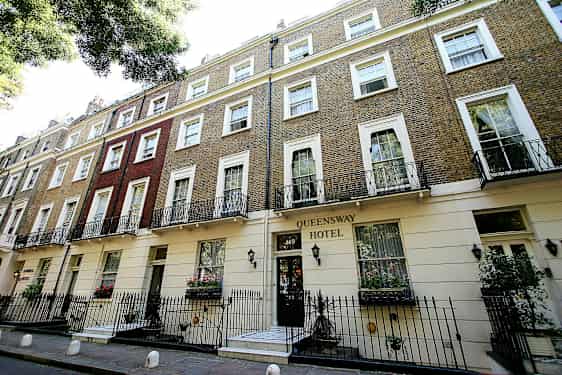 Bild på byggnaden Queensway Hotel med tegelvägg och balkonger. (AI-genererad text)