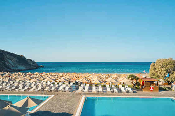 En pool framför en strand med solstolar och parasoller, och havet i bakgrunden. (AI-genererad text)