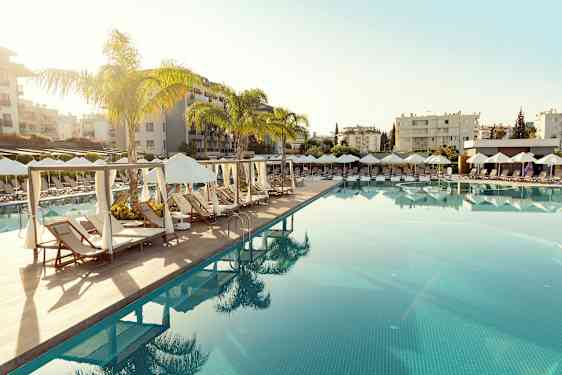 En pool med solstolar och parasoller i en resortmiljö. (AI-genererad text)