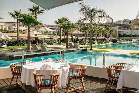 Ett uppdukat bord vid en pool på ett hotellområde. (AI-genererad text)