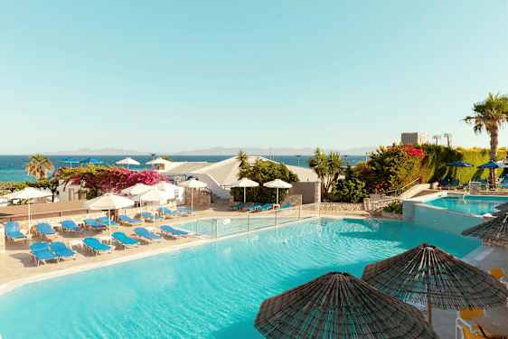 En utomhuspool omgiven av solstolar och parasoll, med utsikt över havet och omgivande vegetation. (AI-genererad text)