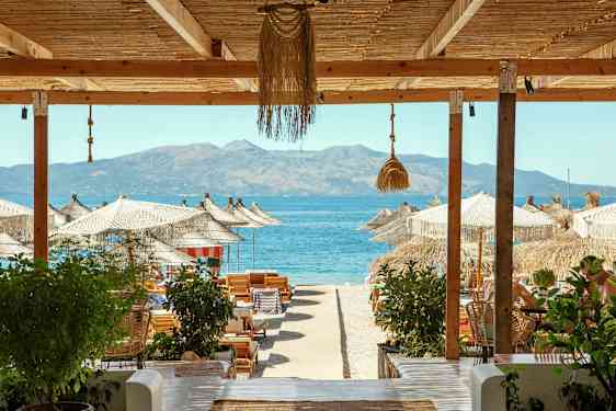 Strandutsikt med parasoller, solstolar och havet i bakgrunden. (AI-genererad text)