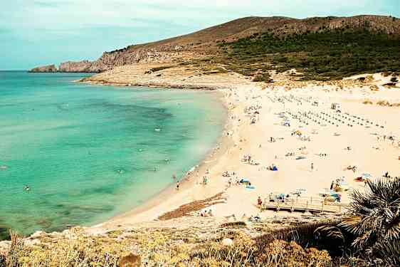 En strand med klart havsvatten, sand och människor som solar och badar. (AI-genererad text)