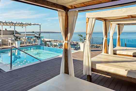 Terrass med pool, cabanas och utsikt över havet. (AI-genererad text)