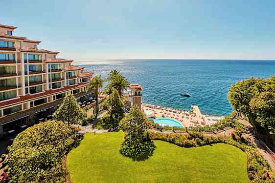 Bild av ett hotell vid kusten, med havsutsikt, poolområde och solstolar. (AI-genererad text)