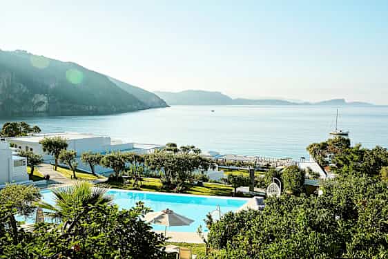 En semesteranläggning vid havet med pool och grönska. (AI-genererad text)