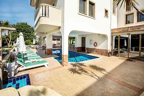 Utomhuspool med omgivande solstolar och en hotellfasad i bakgrunden. (AI-genererad text)