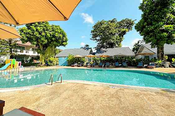 Utomhuspool med solstolar och en lekplats i bakgrunden. (AI-genererad text)