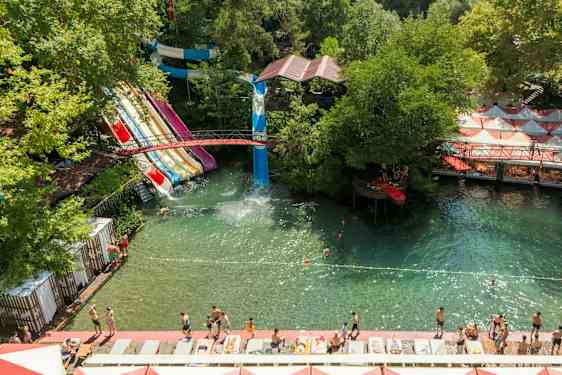Vattenpark med flera vattenrutschbanor och badområde omgiven av grönska. (AI-genererad text)